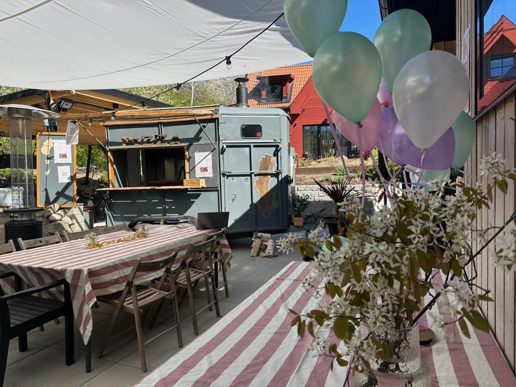 Pizzatrucken på en uteplats med ballonger och randigt dukade långbord