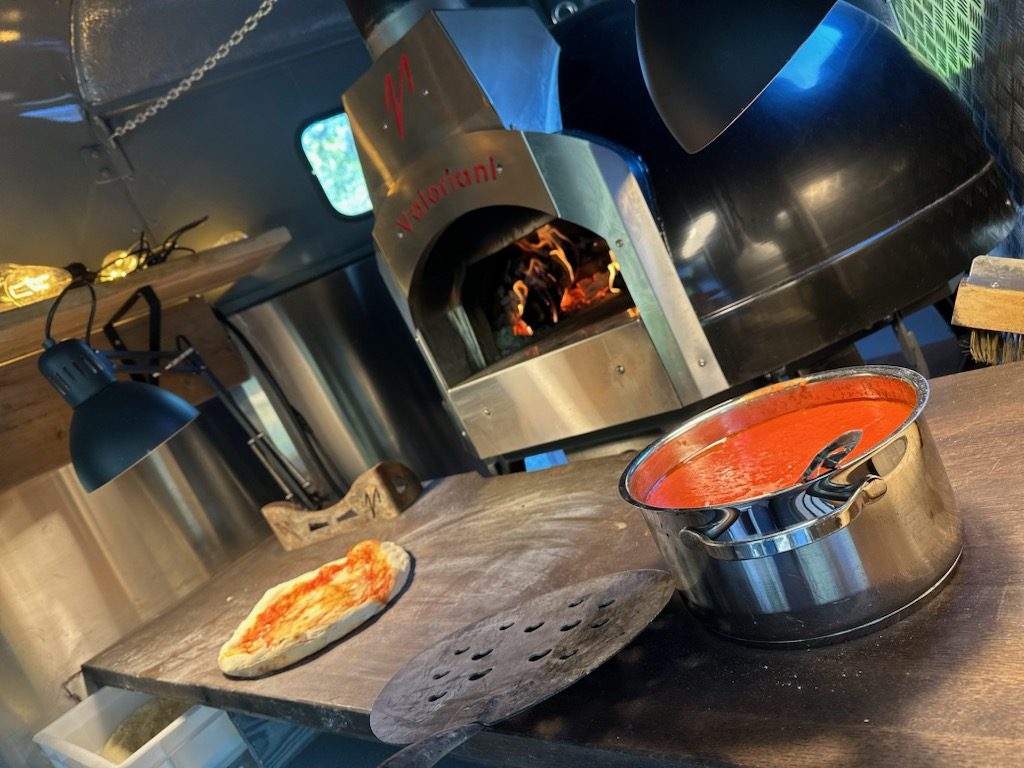 Vedugnen brinner i trucken, en nygräddad bit ligger bredvid kastrullen med tomatsås